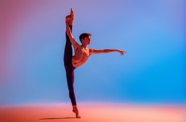 teenage ballet dancer dances barefoot under colored light.