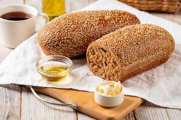Side view on loafs of wheat and rye flour bread with butter on the wooden background