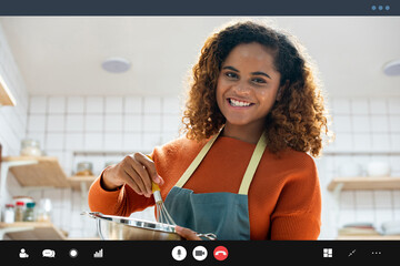 Young African American woman teaching cooking online via video call in kitchen at home