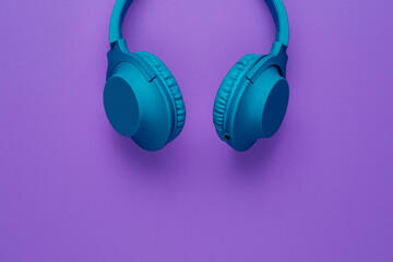 Cool blue wireless headphone on purple background. Music concept.