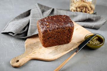 Loaf of rye whole grain bread with pesto sauce on the gray background