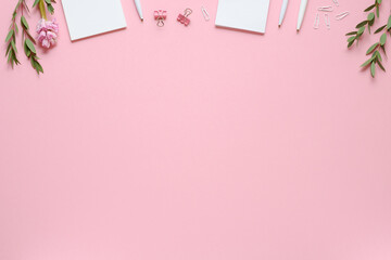 Workspace with notepad, pen, paper clips, eucalyptus and hyacinth on pink background