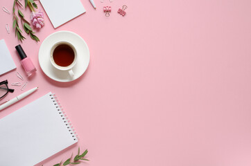 Workplace with notepad, pen, coffee cup and other accessories on pink background