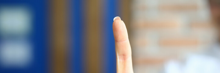 Close-up of person showing finger on camera. Adult with index finger pointing up. Woman with fresh french manicure. Good job. Business and career growth concept