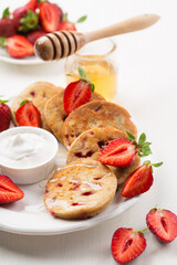 Homemade oatmeal gluten free pancakes with fresh strawberries and honey on white wooden rustic table.