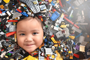 Little asian girl looking at camera surrounded by toy bricks block. Concept of Child development
