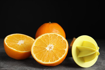 Fresh ripe oranges and reamer on grey table, closeup