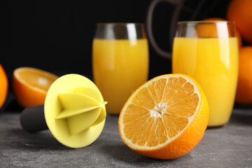 Cut fresh ripe orange, reamer and juice on grey table, closeup
