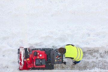 Worker cleaning snow on the sidewalk with a snowblower. Wintertime