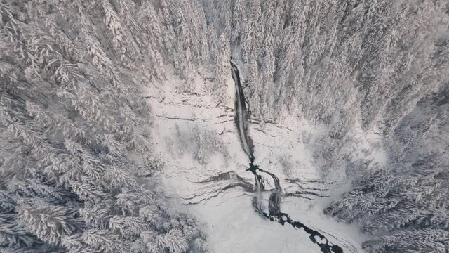 Aerial View Of Snowy Trees And Landscape Around Cascade du Rouget (Rouget Waterfall) In The Giffre Valley In Sixt-Fer-a-Cheval In France During Winter. fast drone shot