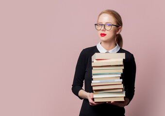 Blonde woman in black dress with books on pink background