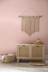 Wooden commode near pink wall in room. Interior design