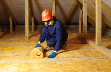 Worker insulate the attic with mineral wool - obrazy, fototapety, plakaty