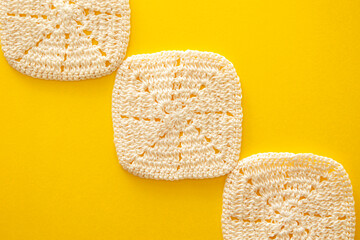 黄色い背景に置いた四角形のレースのコースター３つの構成