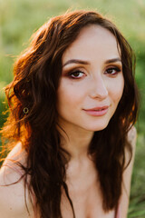 Close-up of a beautiful young woman in a field at sunset.