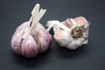 Two garlic heads on a black background.