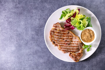 grilled beef steak with sauce and salad