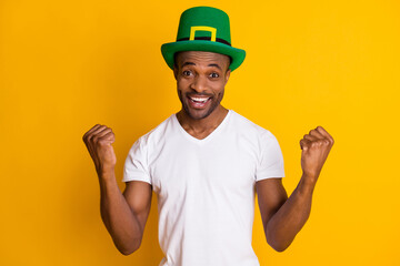 Astonished positive cheerful afro american guy win saint patrick competition impressed delighted raise fists scream wear white green hat outfit isolated bright shine color background