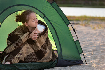 Happy beautiful woman enjoys sunny morning in camp. Concept of travelling, hiking, camping