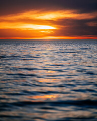 Obraz premium Low angle view looking out to a calm sea as the sun sets.
