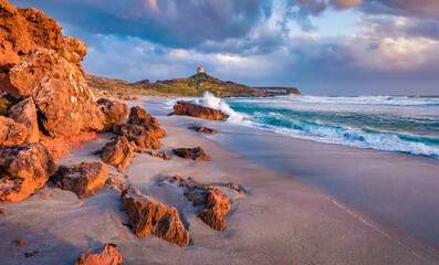 Purple morning light on Capo San Marco Lighthouse on Del Sinis peninsula. Unbelievable summer sunrise on Sardinia, Italy, Europe. Perfect seascape of Mediterranean sea.