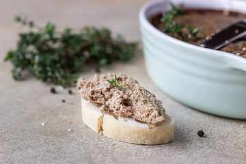 Ciabatta with chicken or turkey liver pate with thyme, concrete background.
