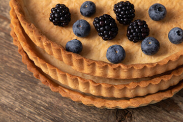 Top view of empty tart shell decorated with berries on wooden table 