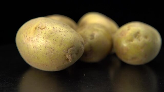 Raw potatoes on a black background close up