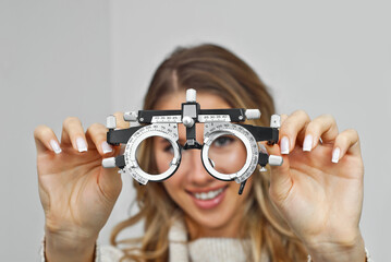 A woman demonstrates an ophthalmic device. The blonde tries on medical equipment for vision...