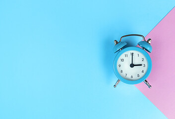 Retro alarm clock on blue background with copy space.