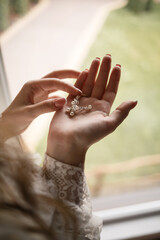 The bride holds earrings in her hand on her wedding day. Jewelry for a holiday for the newlyweds