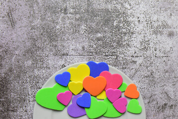 Valentine, love, special day. Multi-colored hearts on a white plate. Stone background and copy space.