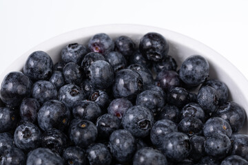 white bowl full with fresh blueberries on white background 