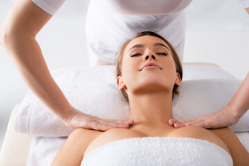 Fototapeta na wymiar female masseur doing massage to pleased client in spa salon