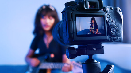 Young woman playing guitar in front of the camera. Streaming online class. High quality photo
