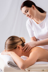 Obraz na płótnie Canvas blurred masseur massaging neck of client lying on massage table