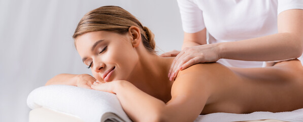 Obraz na płótnie Canvas masseur massaging pleased client lying on massage table, banner