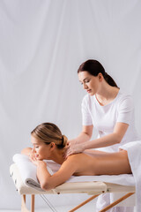 masseur massaging pleased woman on massage table in spa salon