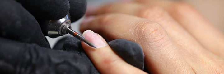 Close-up of professional nail master cleaning clients cuticle. Macro shot of person carefully working with female hand. Beauty salon procedure and nice treatment concept