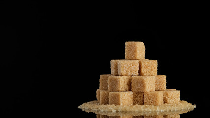 brown sugar cubes on black background. Demerara golden brown sugar