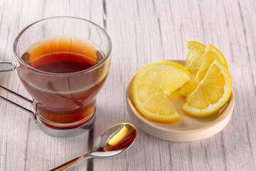 Cup of tea on wooden surface in light tone and white background, lemon slices and teaspoon. tea time concept