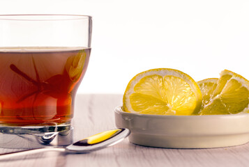 Cup of tea on wooden surface in light tone and white background, lemon slices and teaspoon. tea time concept