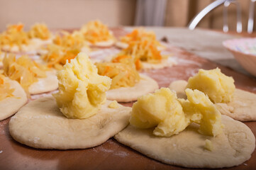 Small cakes of raw dough with filling prepared for the formation of Russian pies. Homemade baking