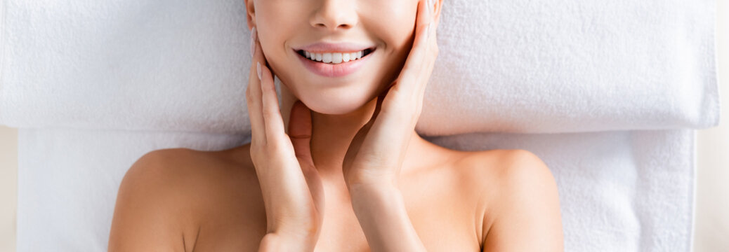 Top View Of Happy Woman Touching Cheeks And Lying On Massage Table In Spa Salon, Banner