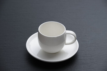 White coffee cup on a black textured stone slab, side view.