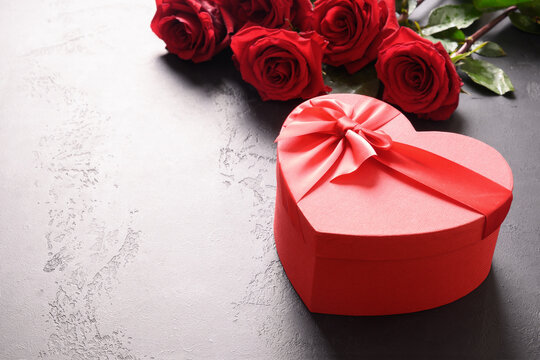 Heart giftbox and red roses on black background with copy space. Close up. Valentine's day greeting card.