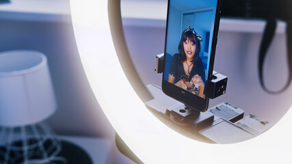 Young woman with black hair recording make up tutorial. Applying make up in front of the camera. High quality photo