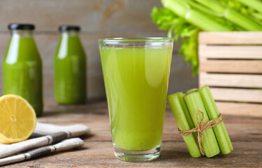 Fresh celery and glass of juice on wooden table, closeup