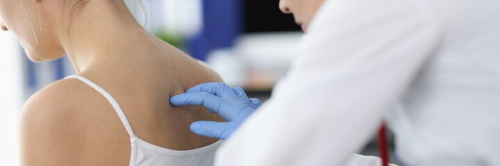 Doctor neurologist in protective gloves palpating patients spine in clinic. Diagnostics and treatment of spinal hernias concept