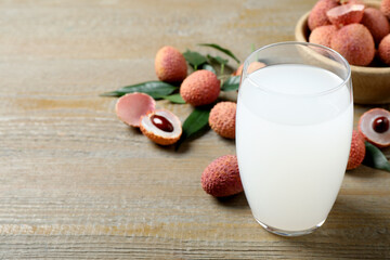 Lychee juice and fresh fruits on wooden table. Space for text